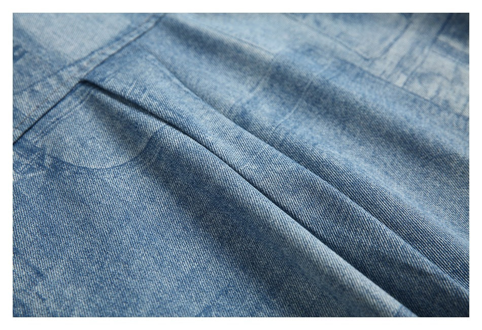 Close-up of folded blue denim fabric with a stitched seam and printed pattern.