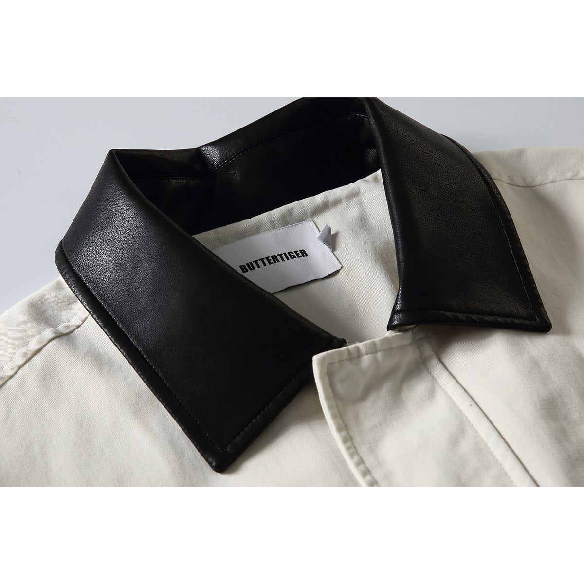 Close-up of an off-white jacket with a wide black collar and a visible inner brand label.
