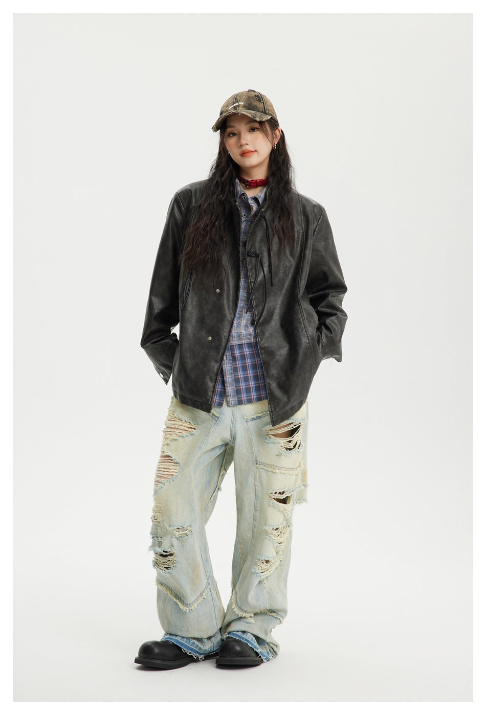 Full-length view of a model wearing a black jacket over a blue plaid shirt and distressed light-wash jeans.