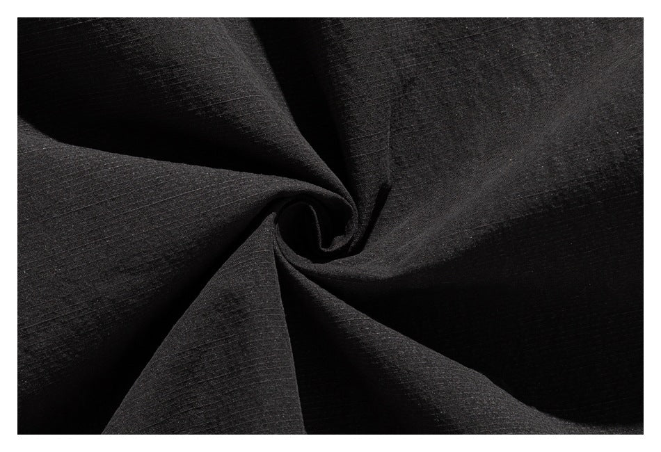 Close-up of black fabric gathered into a twist, showing its subtle grid-like texture.