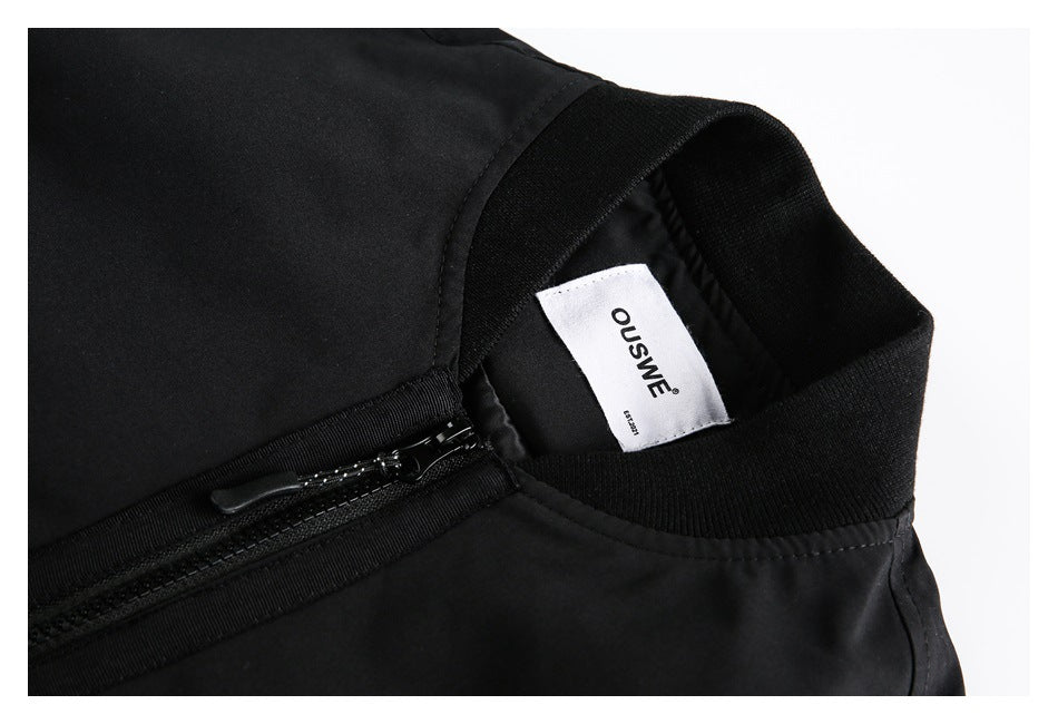 Close-up of the black jacket's ribbed collar, front zipper, and sewn-in white brand label.