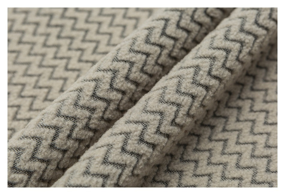 Close-up of fuzzy beige fabric with a repeating dark zigzag pattern and folded edges.