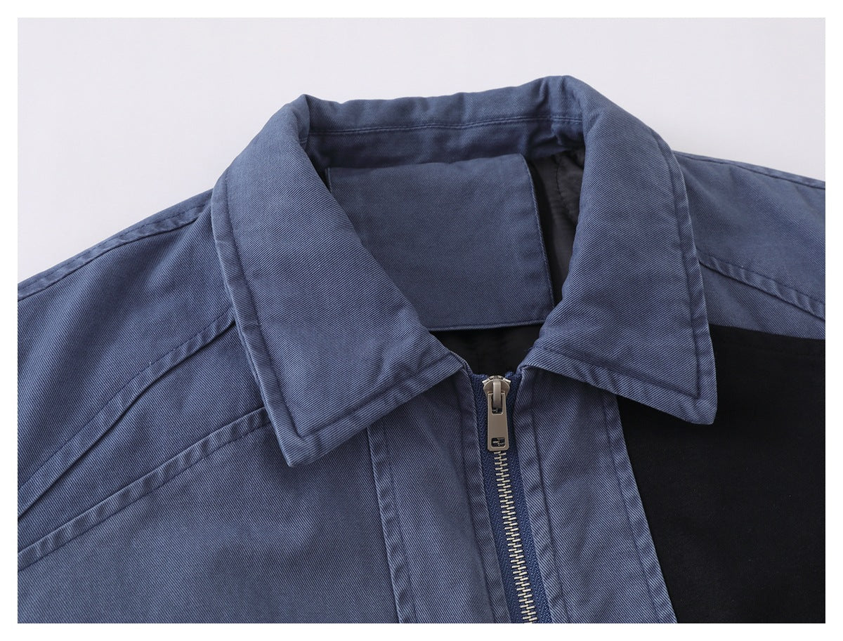 Close-up of a blue jacket's pointed collar, metal zipper and black chest panel.