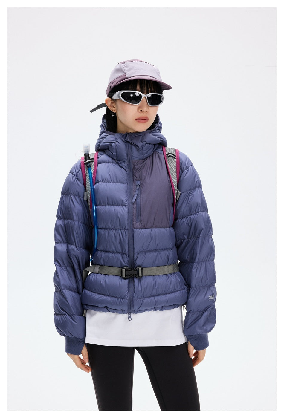 Close-up of model in purple hooded quilted jacket with contrast chest zip pocket and ribbed thumbhole cuffs