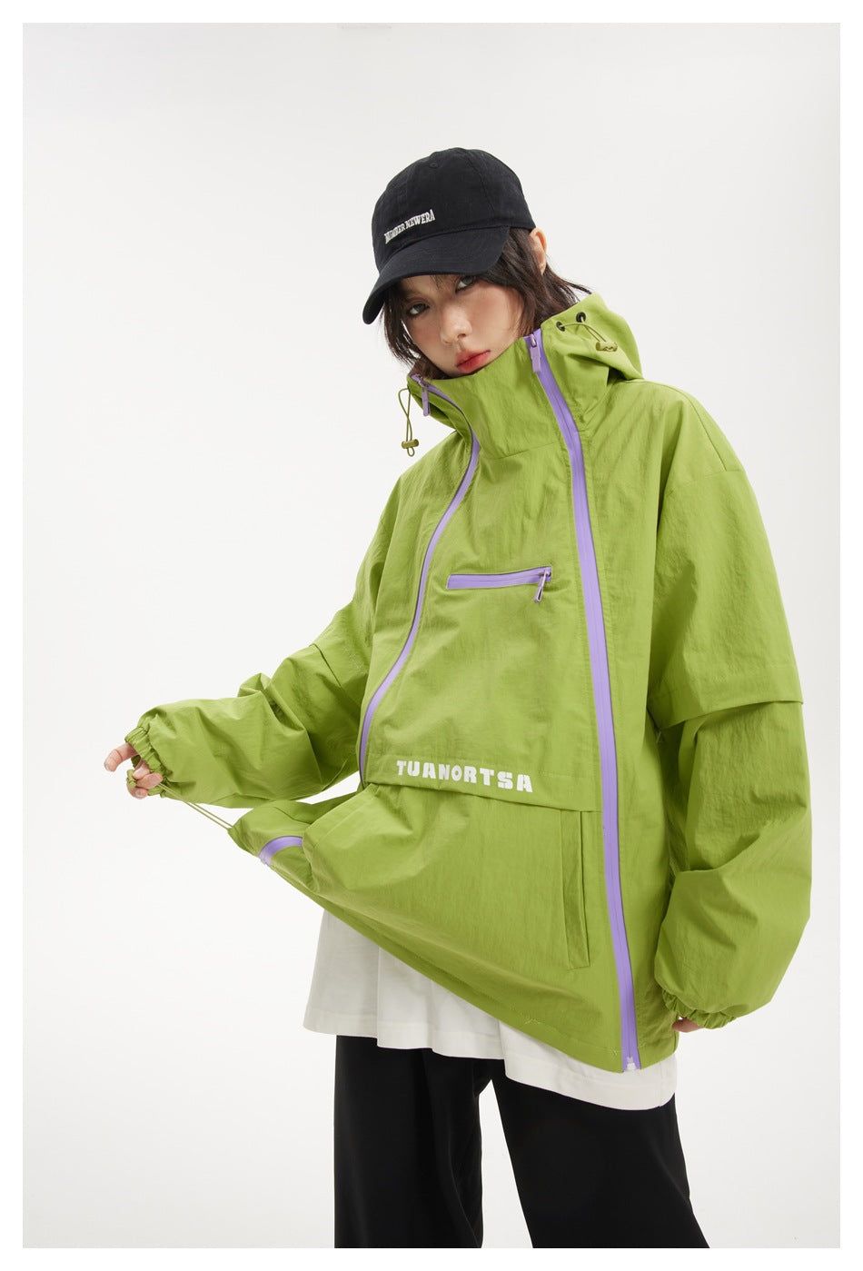 Front view of a model wearing a lime-green jacket with lavender zippers, a high collar, and a hood.