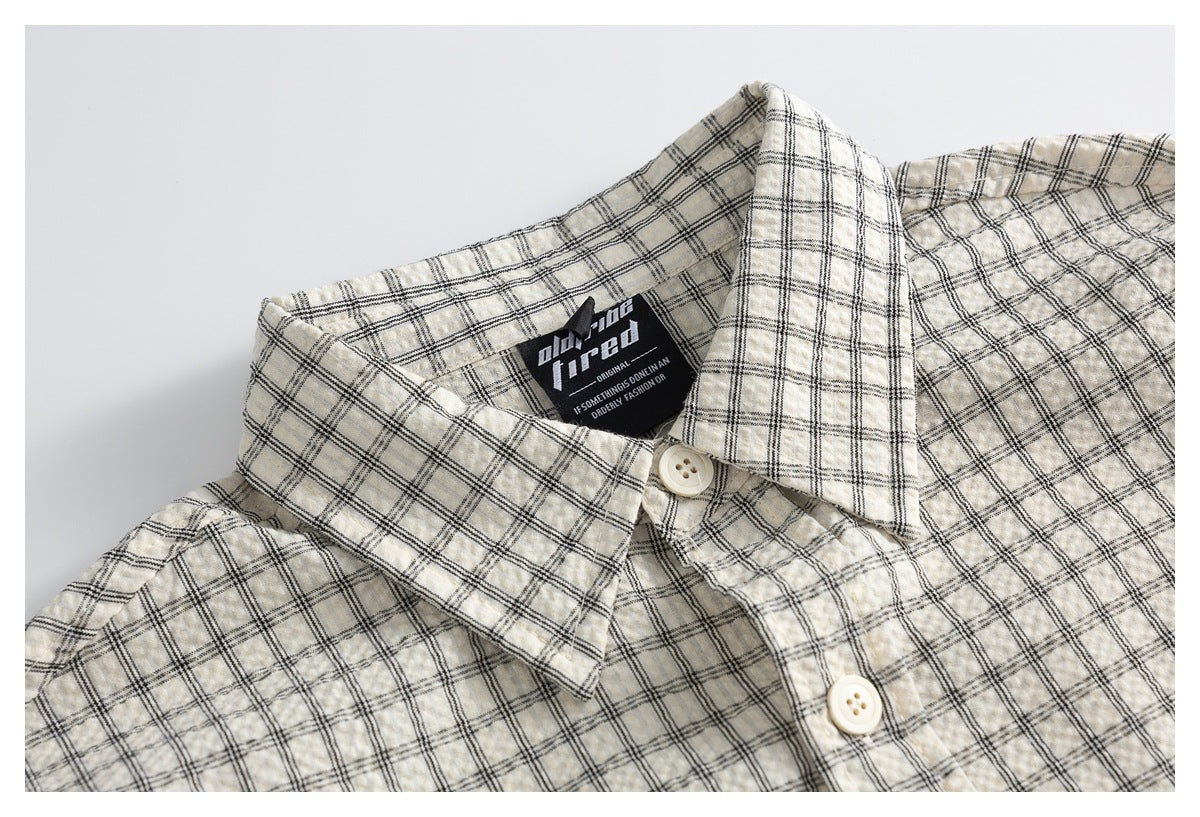 Close-up of an ivory plaid shirt collar and button placket with a black neck label.
