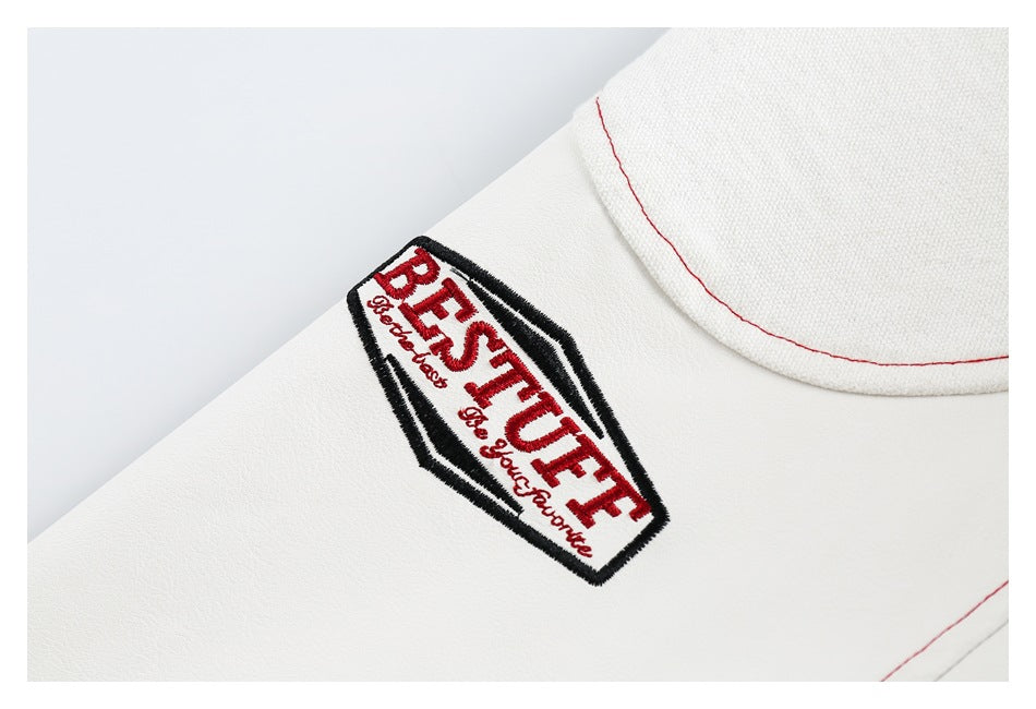 Close-up of a white garment showing a black-bordered embroidered patch with red English lettering.