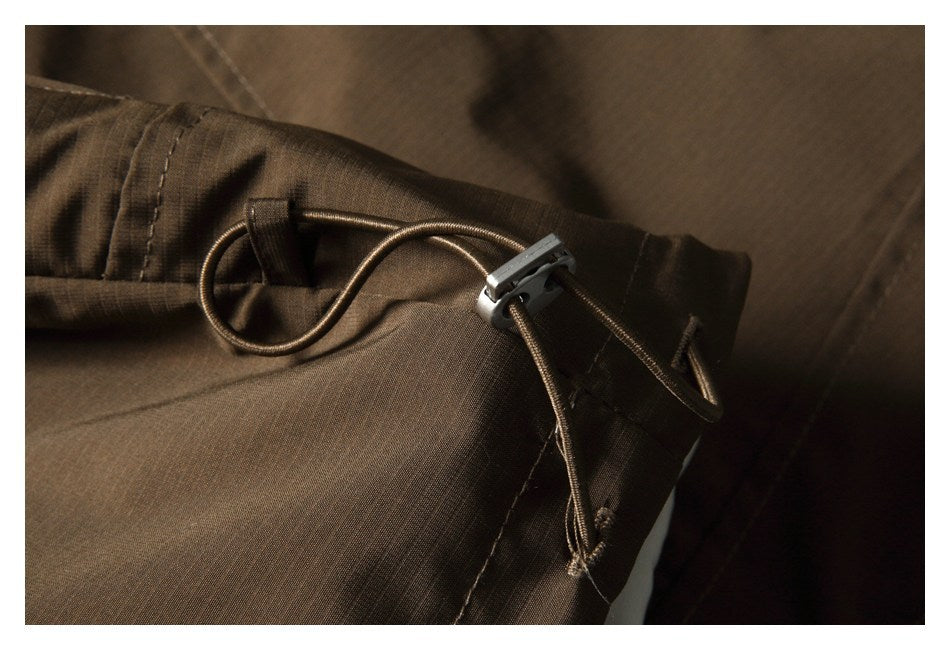 Close-up of a brown garment's drawcord and plastic toggle at a stitched edge.