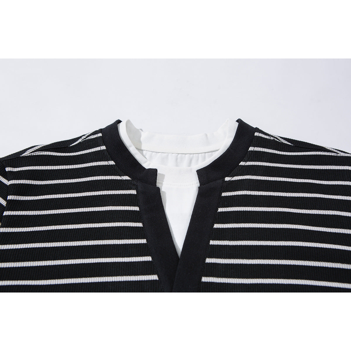 Close-up of a black-and-white striped top with a black-trimmed V neckline and white inner layer.