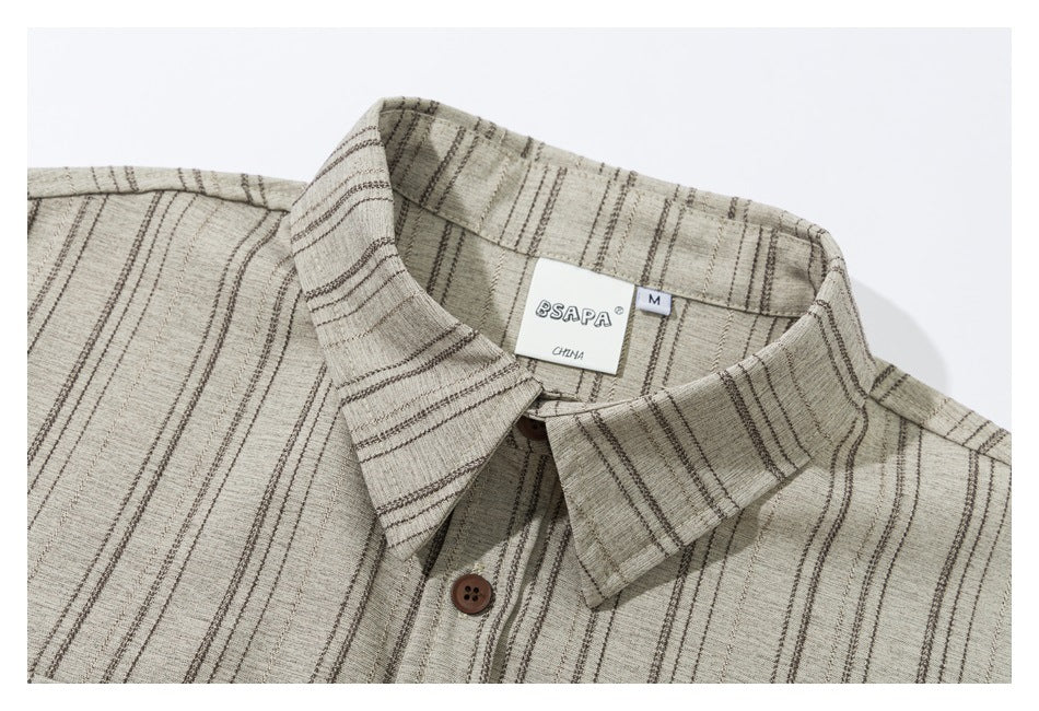 Close-up of a beige striped shirt collar, brown button, and sewn neck label.