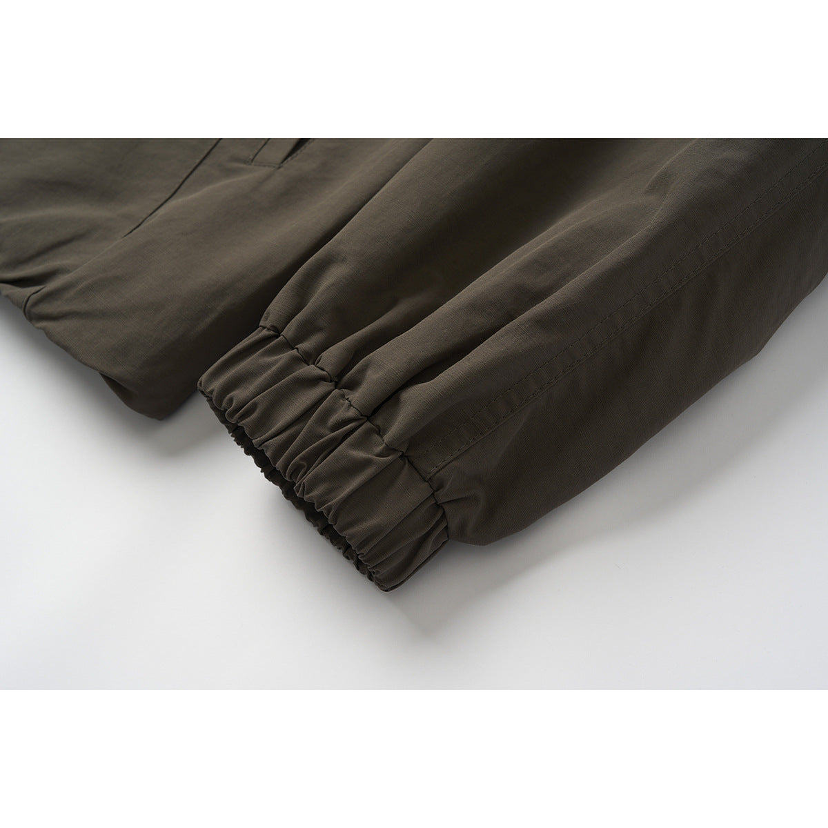 Close-up of the dark brown jacket's gathered elastic cuff and stitched sleeve seam.