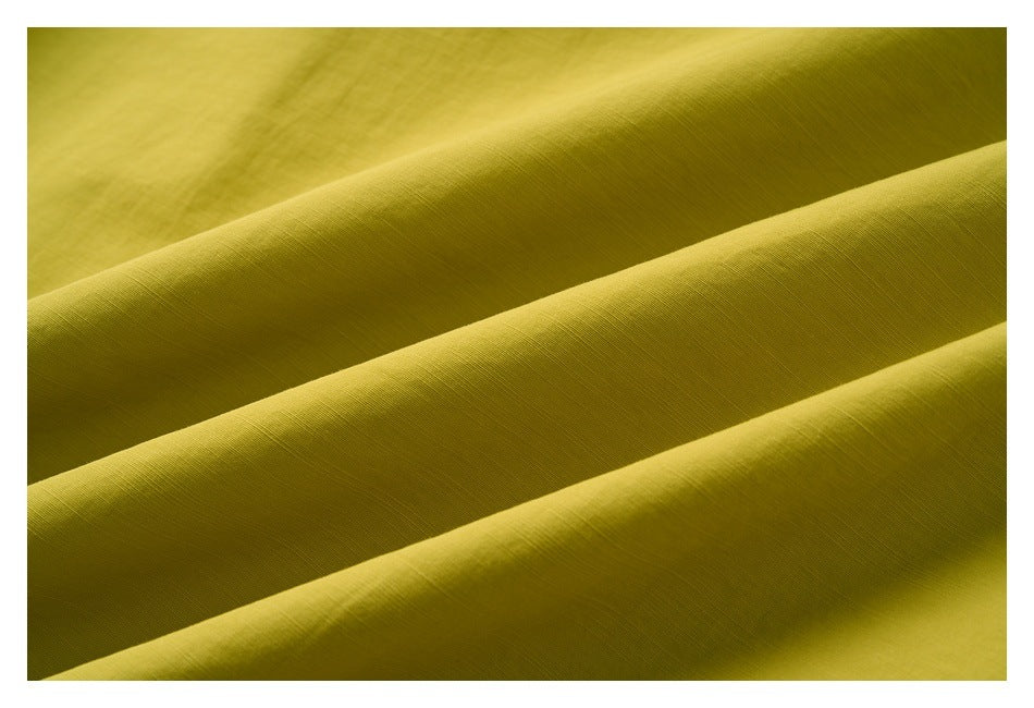 Close-up of the fine surface texture and folds of mustard-yellow fabric.