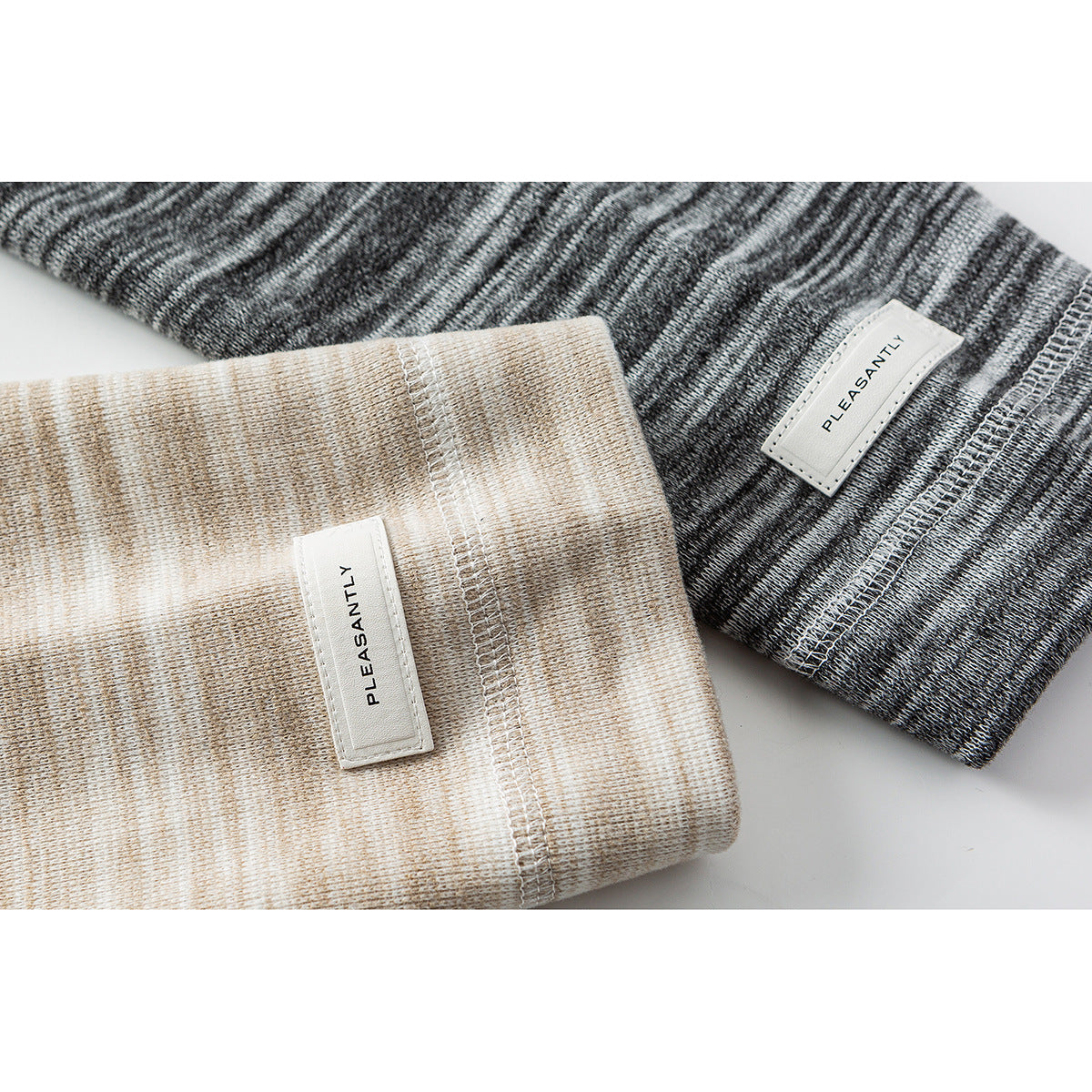Close-up of beige and charcoal heathered shirt cuffs with sewn labels and stitched hems.