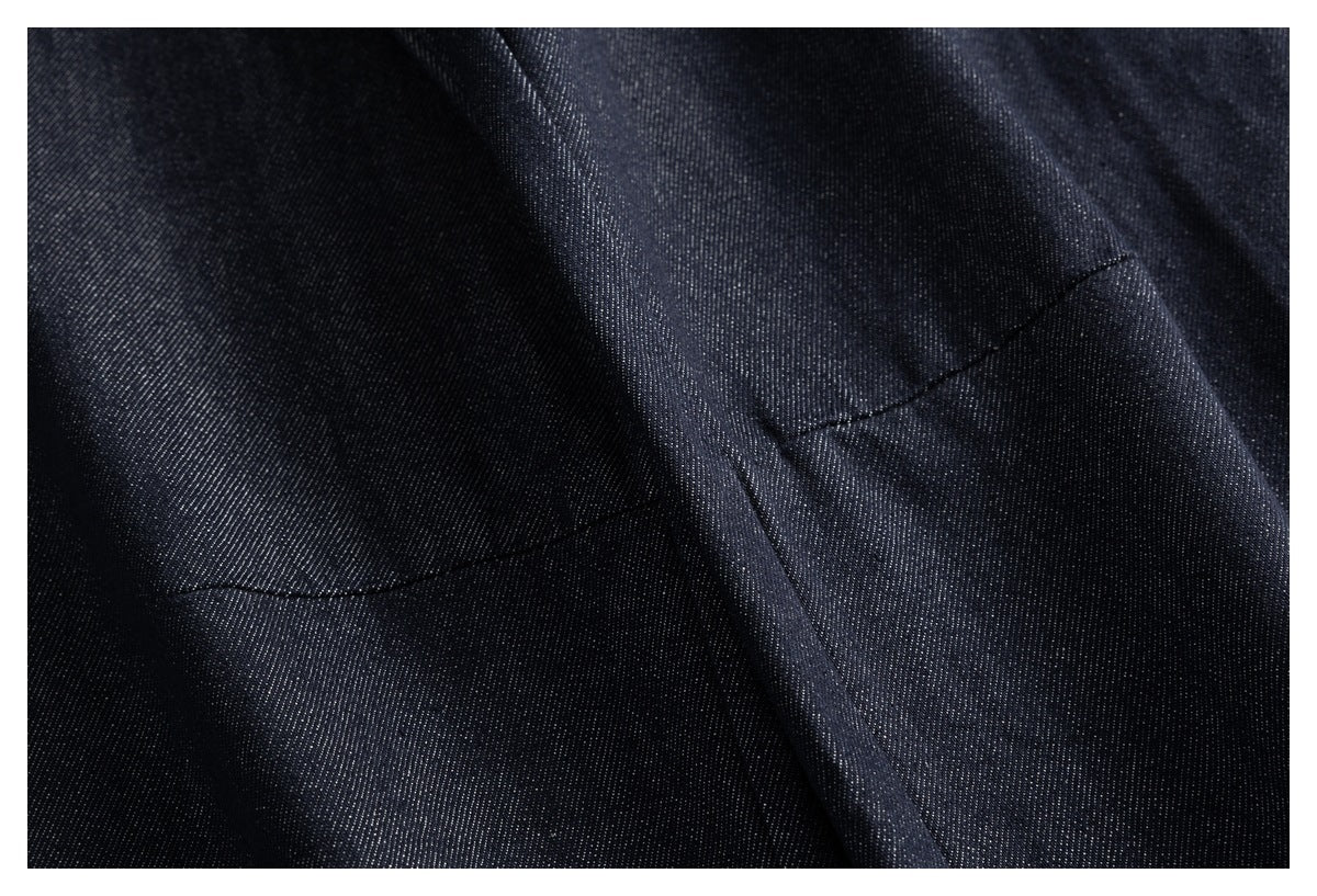 Close-up of dark indigo denim fabric showing a seam and folded construction.