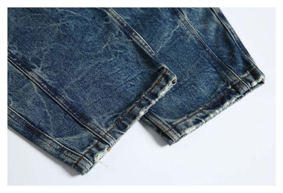 Close-up of faded blue jean leg hems with slightly frayed edges and contrast stitching.