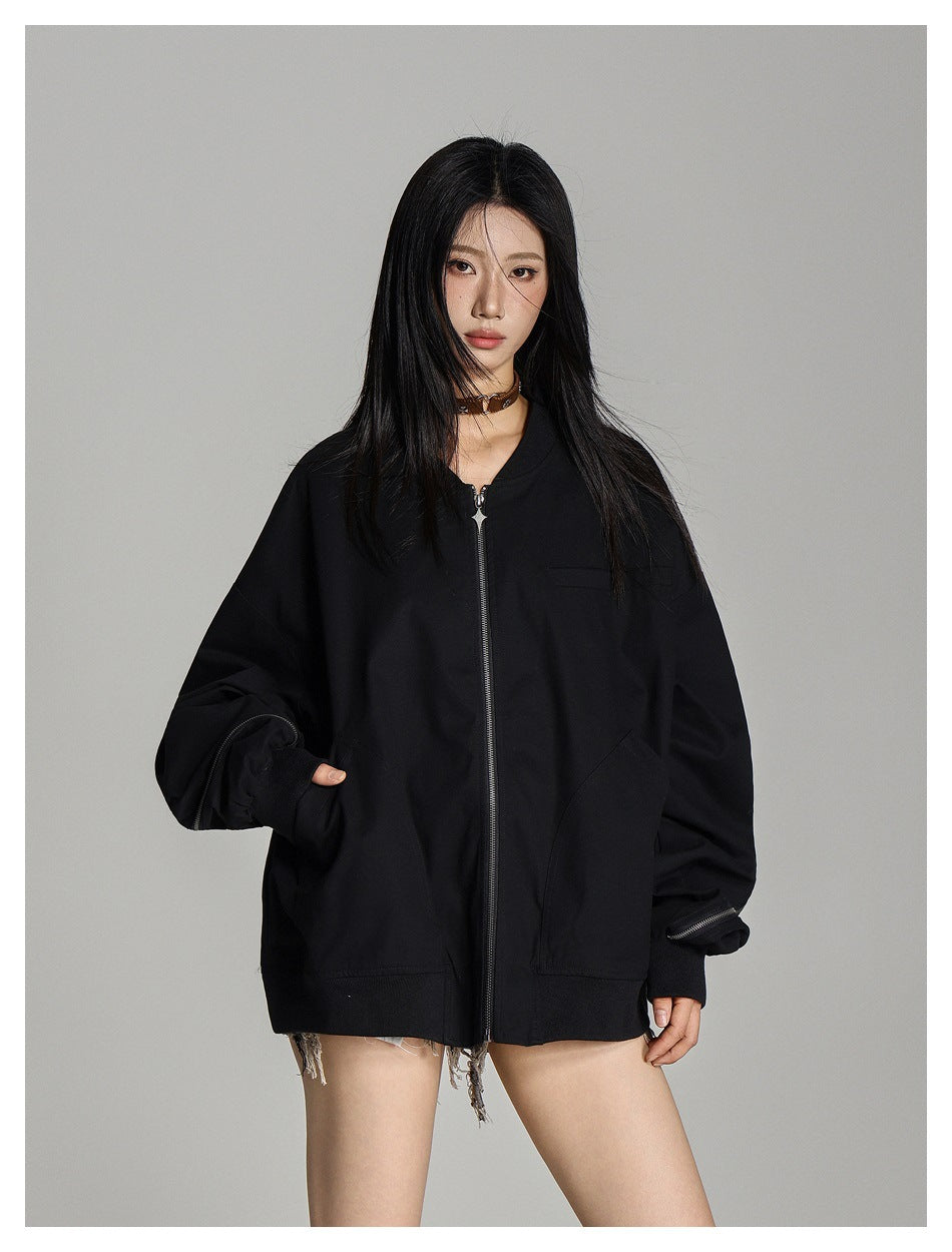 Front view of a model wearing an oversized black zip-front jacket with large pockets and zippered sleeve details.