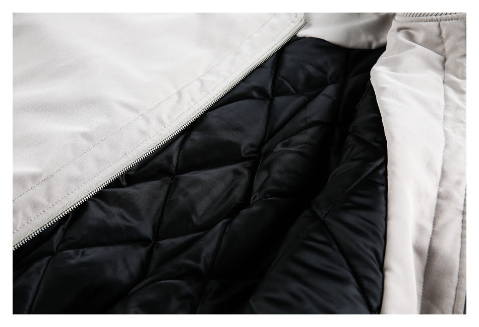 Close-up of a light-colored jacket opened to show its black diamond-quilted lining and zipper.