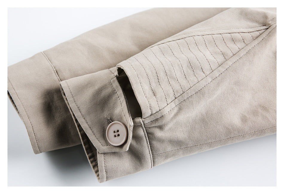 Close-up of a beige garment cuff with a buttoned tab and rows of stitching.