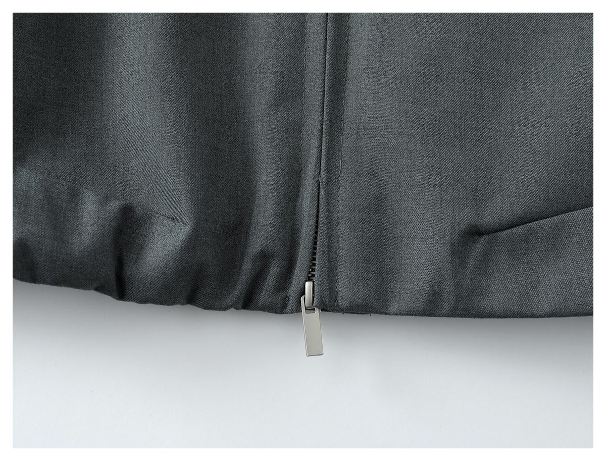 Close-up of a dark gray garment hem with a vertical zipper and silver pull.