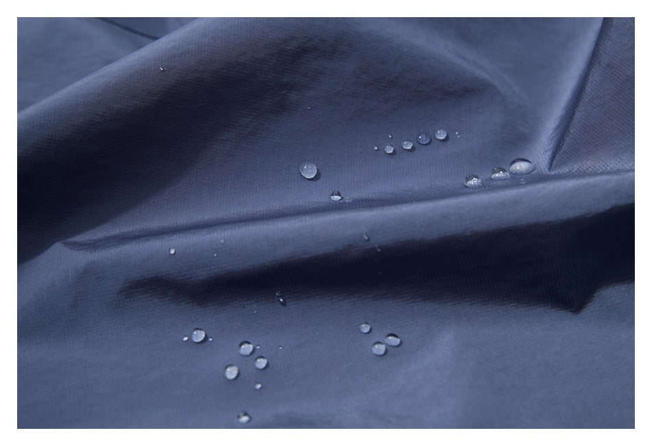 Water droplets bead on close-up slate-blue jacket fabric.