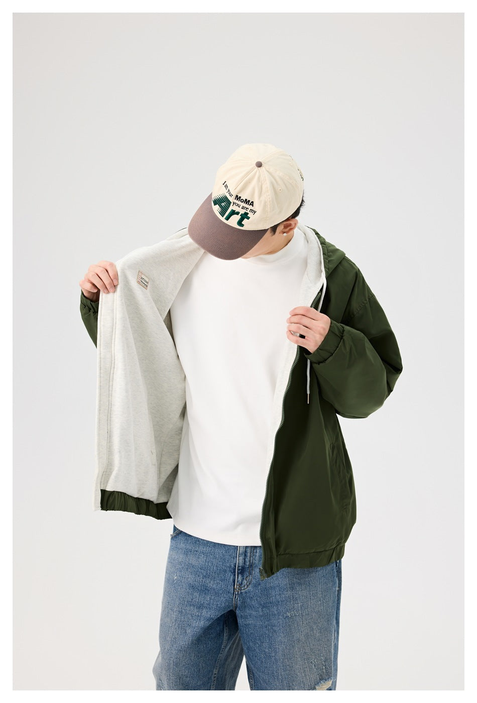 Model opens a dark green hooded jacket to show the light gray interior and contrasting panels.