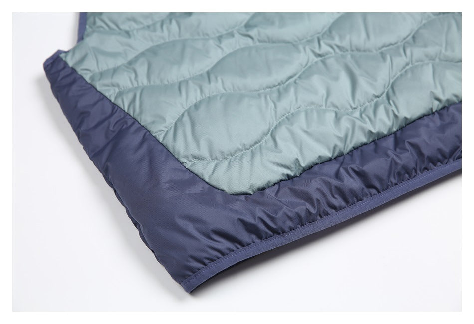 Close-up of a sage-green quilted garment panel with a dark navy border and bound edge.