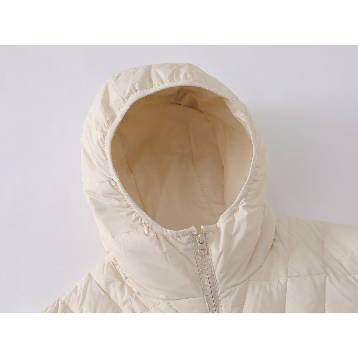 Close-up of an ivory quilted jacket showing its hood, lining, and front zipper.