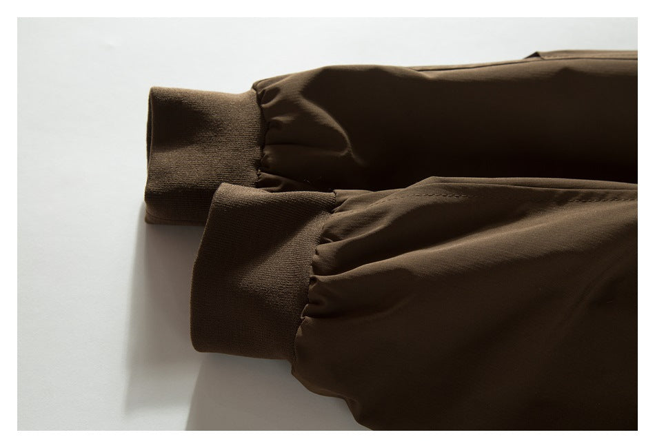 Close-up of two gathered sleeves with wide ribbed cuffs on a dark brown jacket.