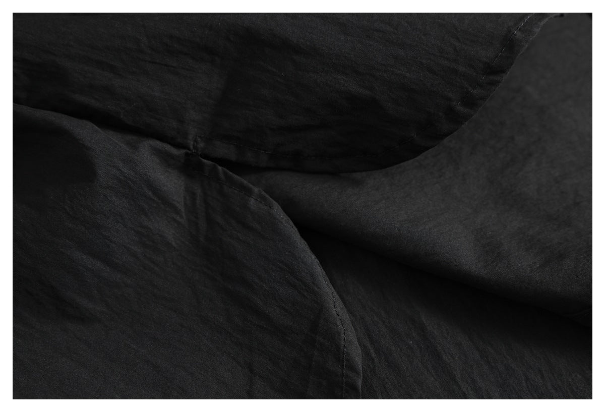 Close-up of overlapping black shirt fabric and stitched seams.