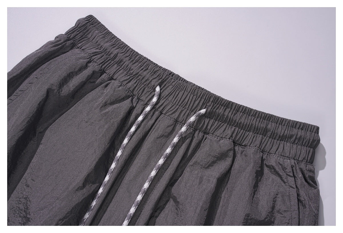 Close-up of the gathered elastic waistband and two white drawcords on charcoal gray pants.