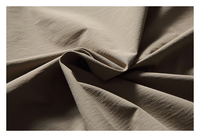 Close-up of taupe fabric draped into folds, showing its subtle surface texture.