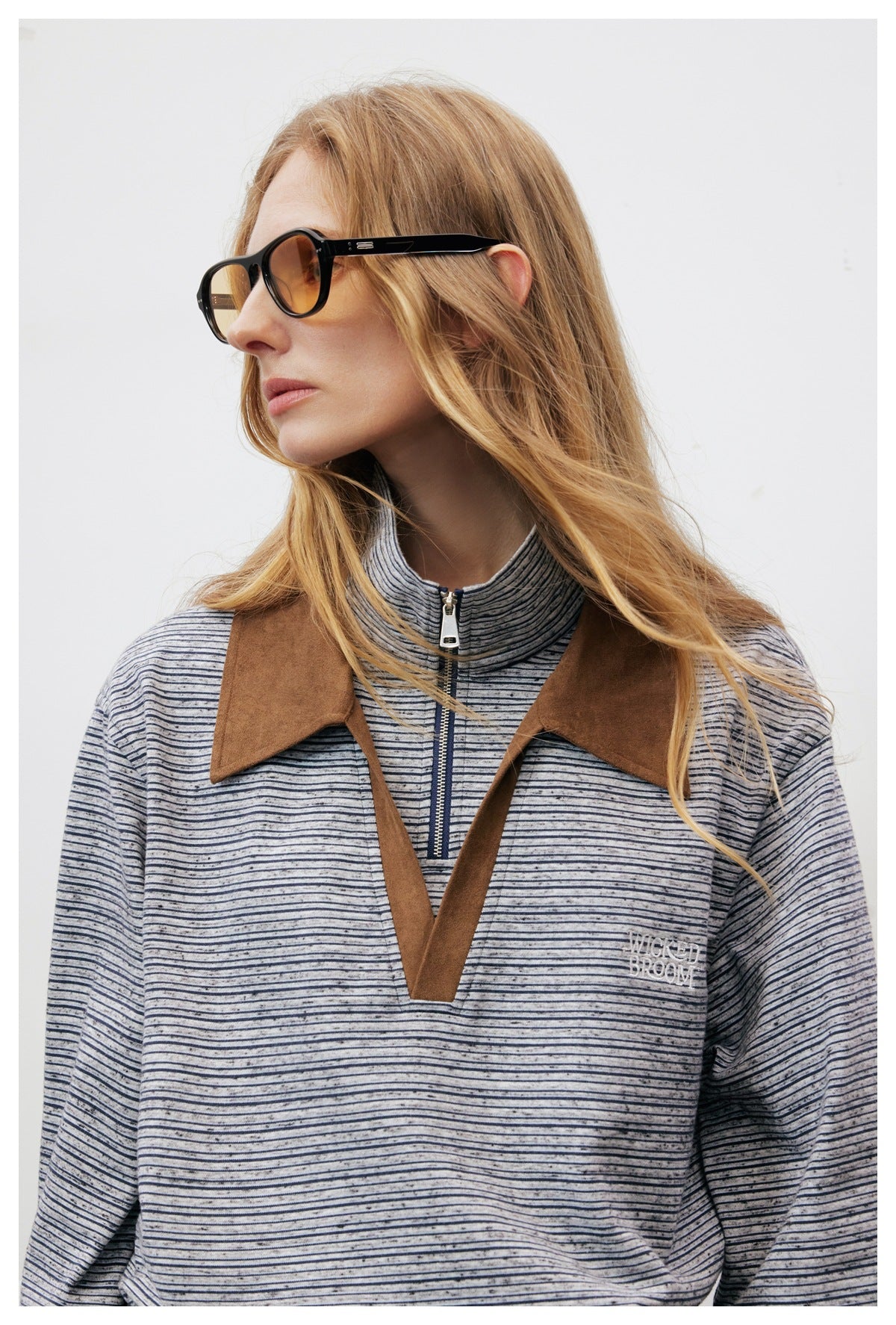 Close-up of a woman wearing a gray striped pullover with a brown collar, zip neck and V-shaped placket.