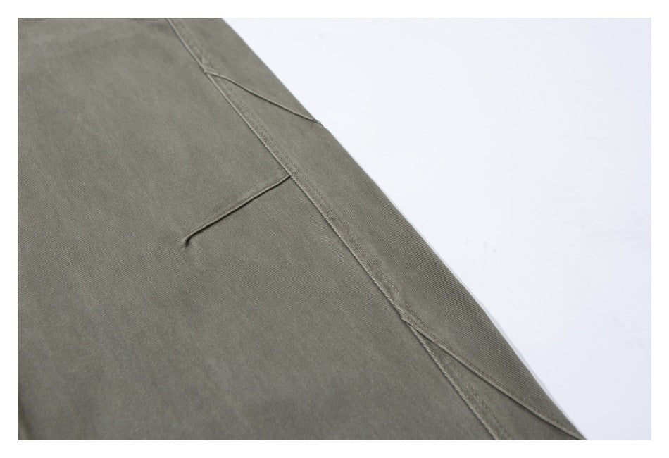 Close-up of olive-gray pants showing a stitched seam and a small slit pocket.