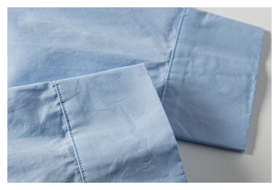Close-up of light blue garment fabric with a wide folded cuff and neat edge stitching.