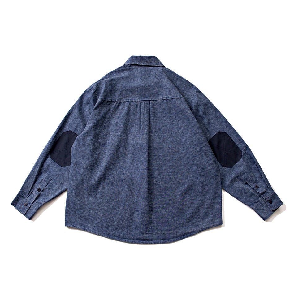 Back view of blue washed button-up shirt with center pleat and navy octagonal elbow patches