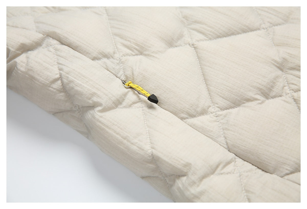 Close-up of cream quilted jacket fabric with a yellow cord zipper pull and black tip.