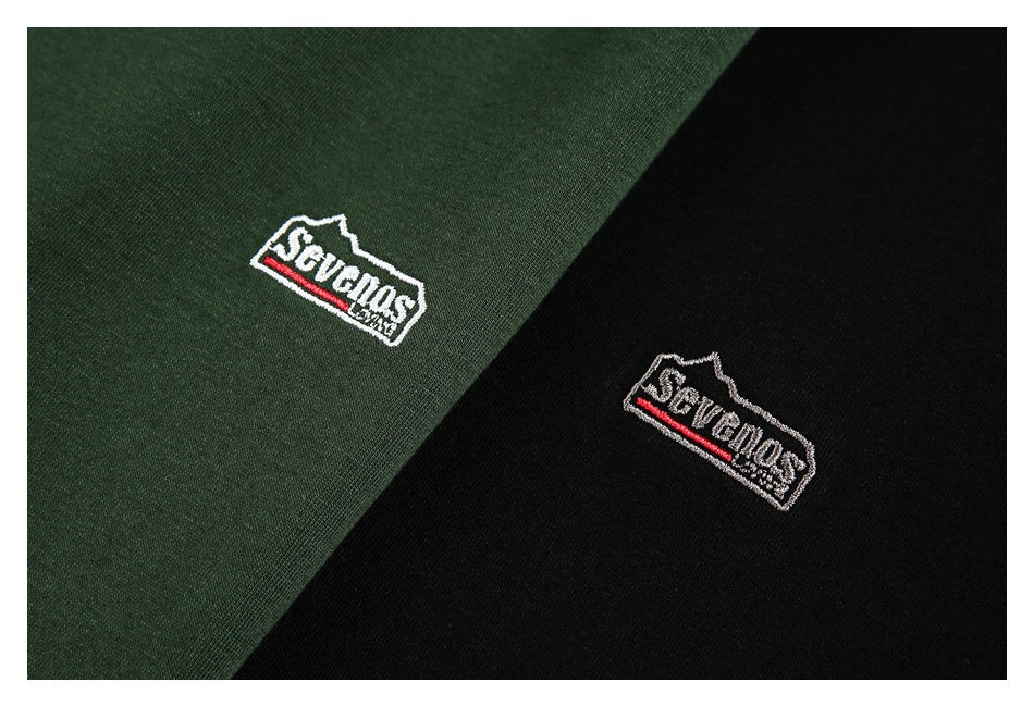 Close-up of matching embroidered chest logos on dark green and black tops.