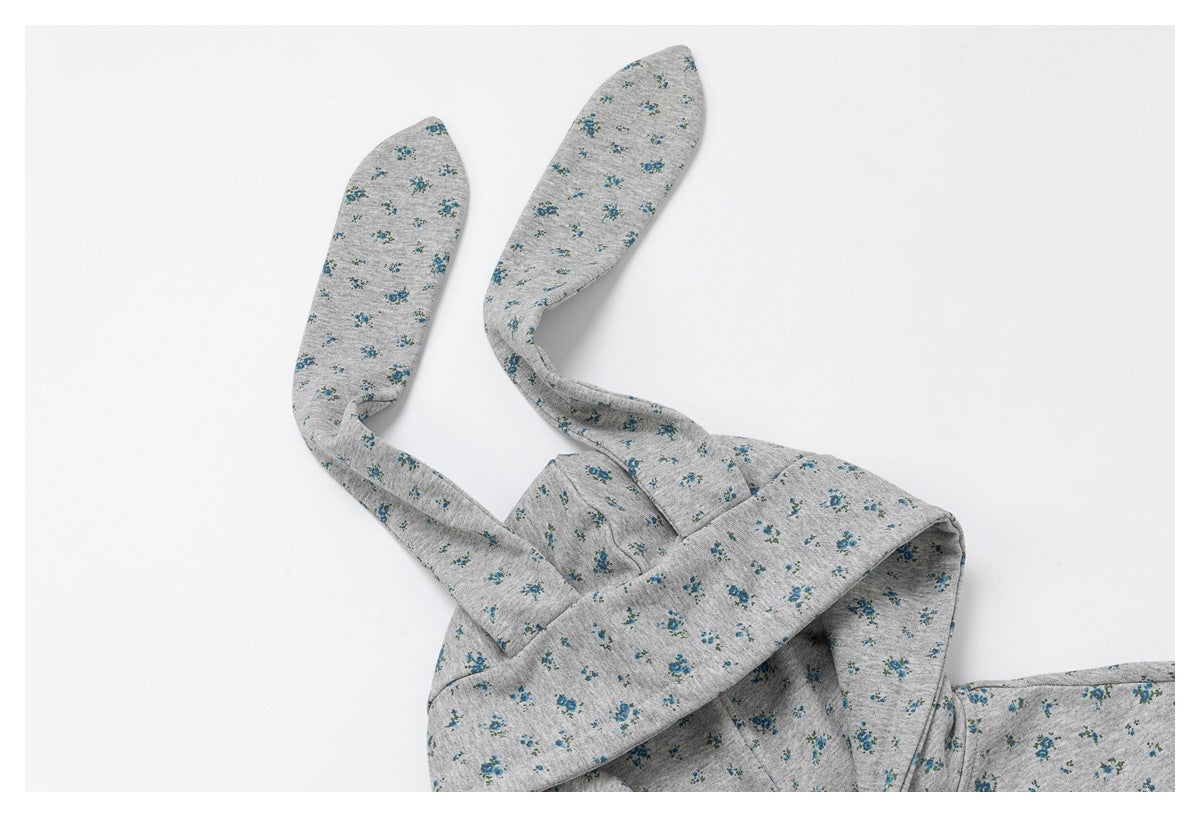 Close-up of a gray hoodie with small blue floral print and long matching hood ears.