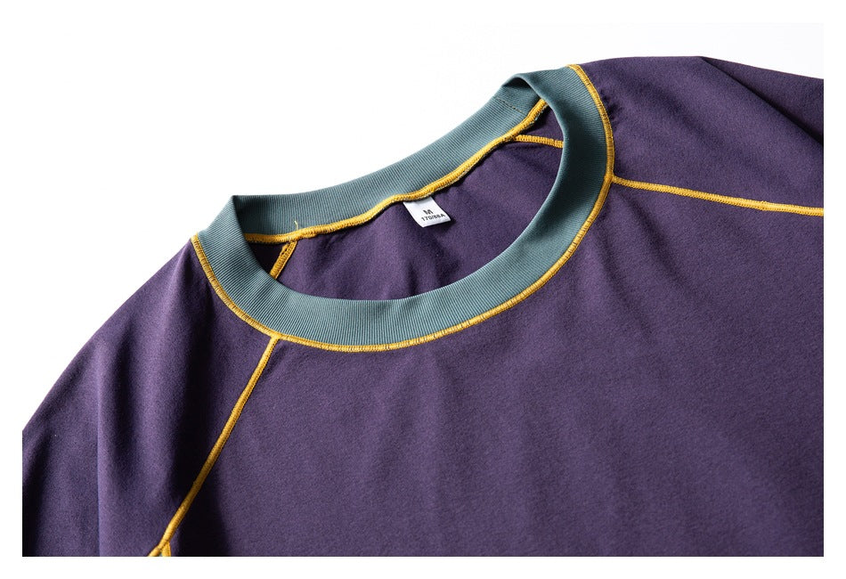 Close-up of the purple T-shirt's teal crew neck, yellow stitching, and small inner label.