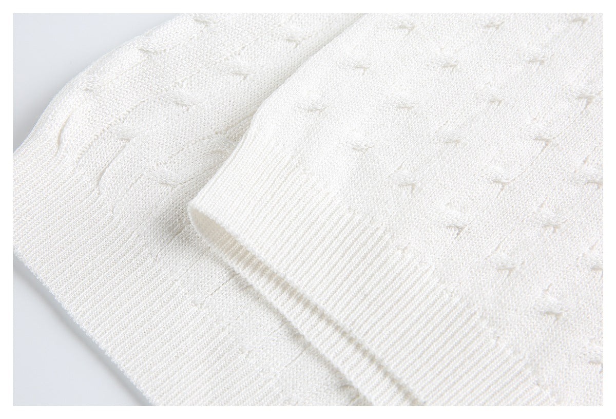 Close-up of an ivory knit sleeve cuff with wide ribbing over the textured garment body.