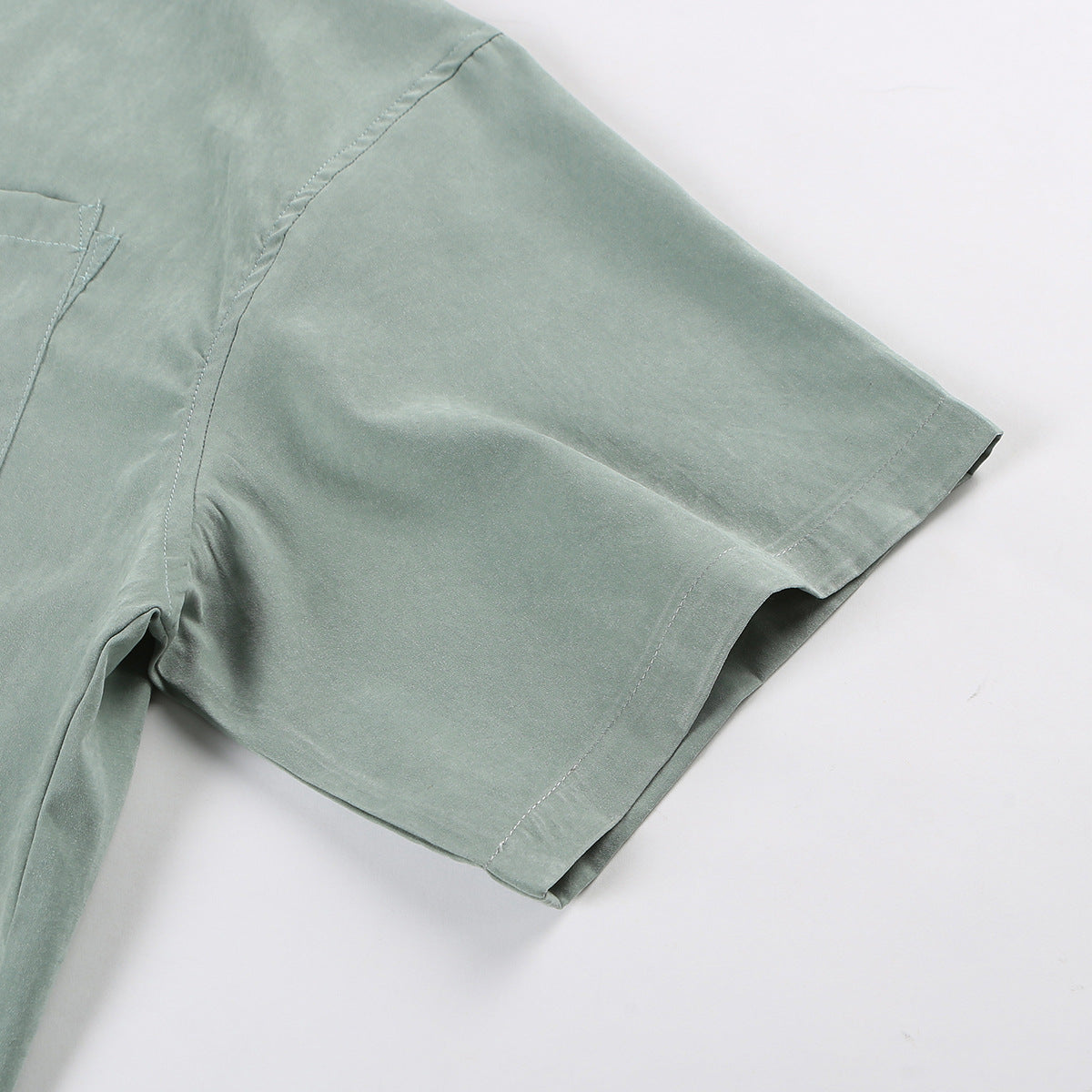 Close-up of a sage-green short sleeve and its stitched cuff.