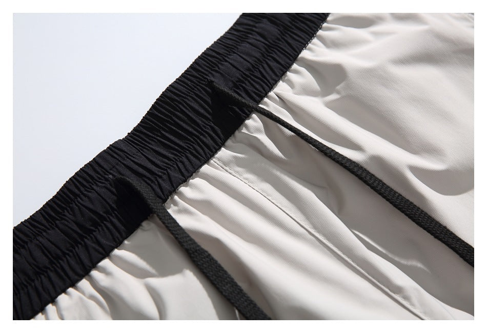 Close-up of the black elastic waistband, black drawstrings, and light gray shorts fabric.