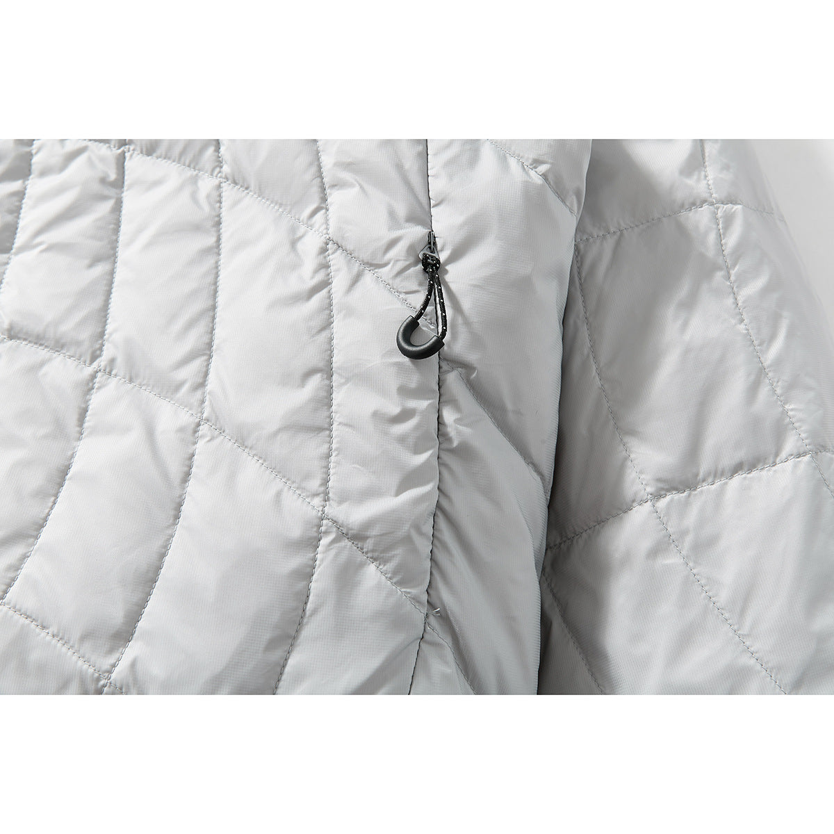 Close-up of the light gray jacket’s quilted front and a black cord zipper pull.