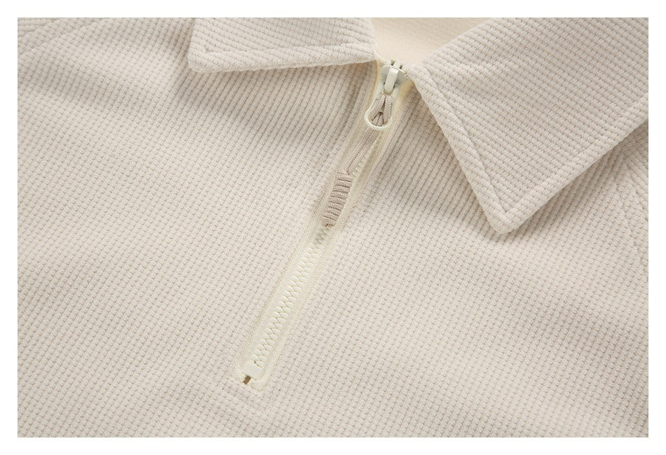 Close-up of the cream top's quarter zipper, pointed collar, and textured fabric.