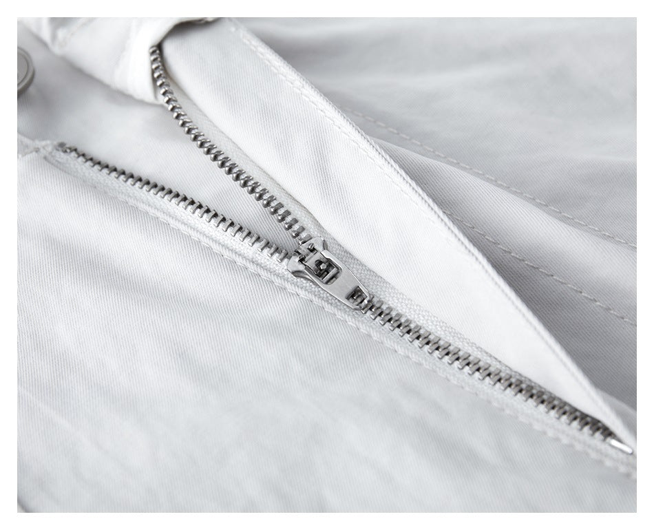 Close-up of white trousers showing the metal zipper fly and stitching.