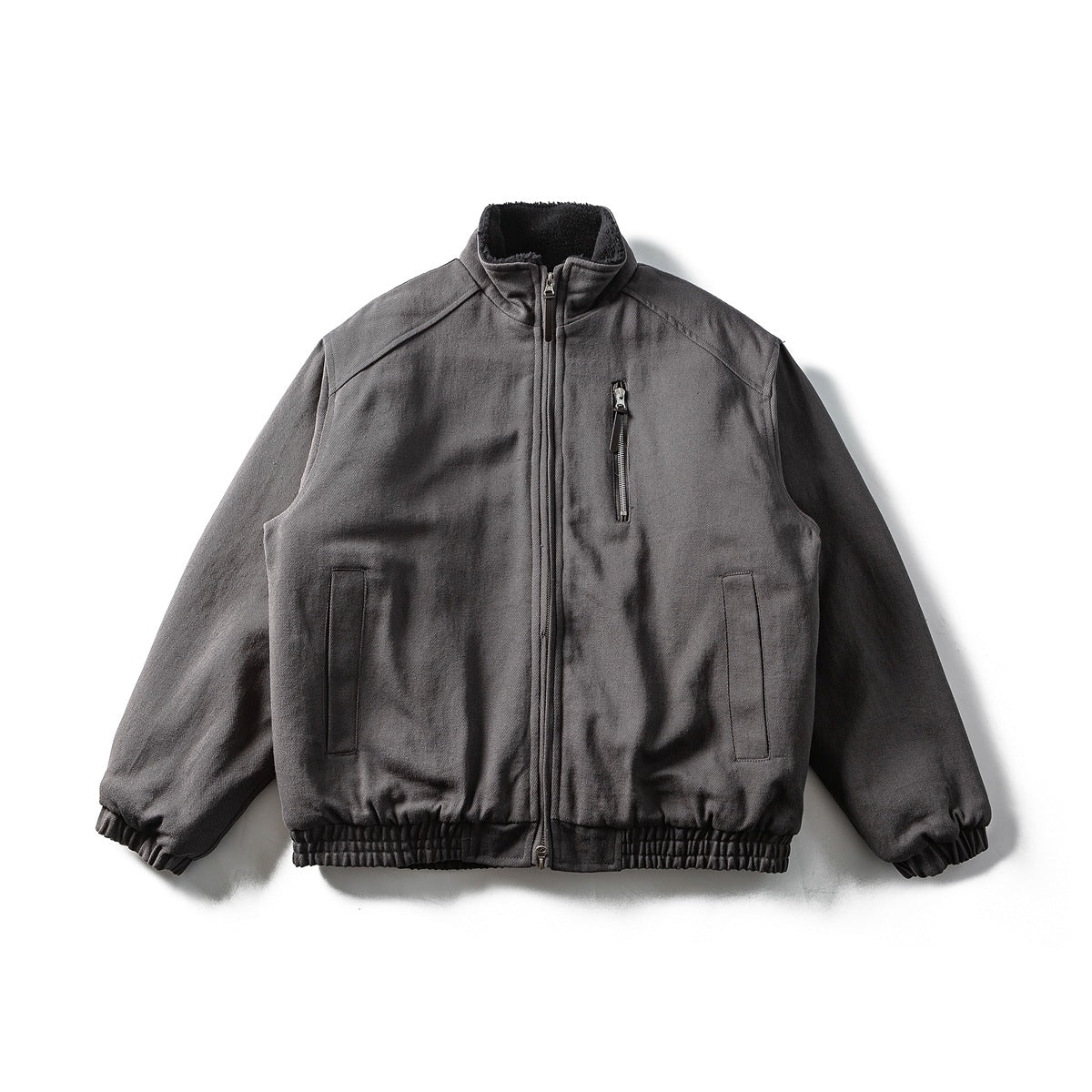 Dark gray zip-up bomber jacket laid flat, zipped, with stand collar, chest zip pocket and ribbed hem