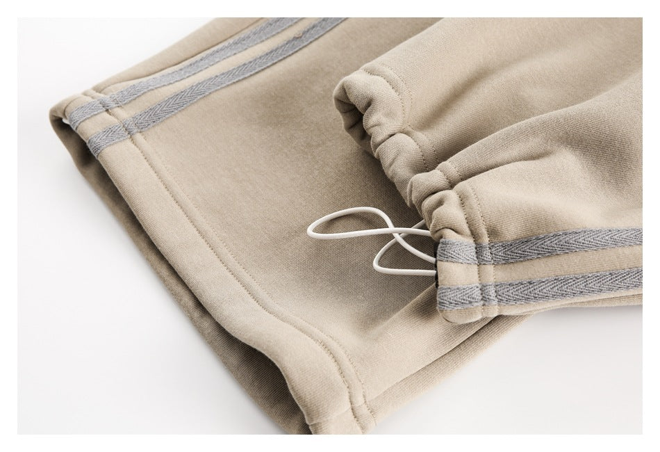 Close-up of beige pants showing a gathered cuff with a white drawcord and gray trim bands.