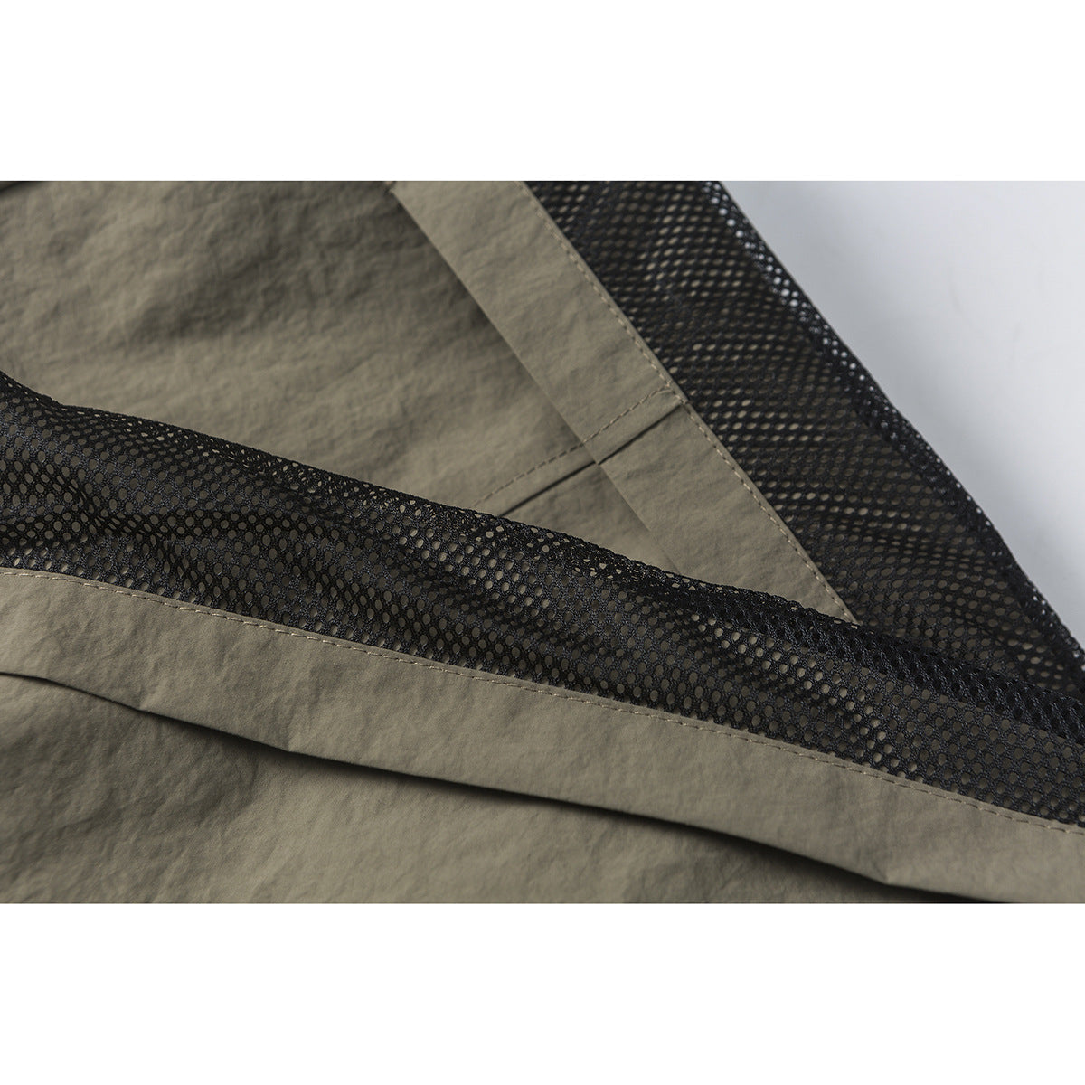 Close-up of black mesh lining and stitched olive-gray fabric inside the shorts.