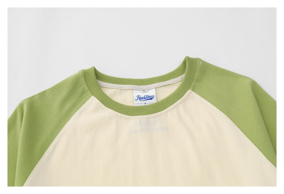 Close-up of a cream T-shirt with a green ribbed crew neck and a visible woven neck label.
