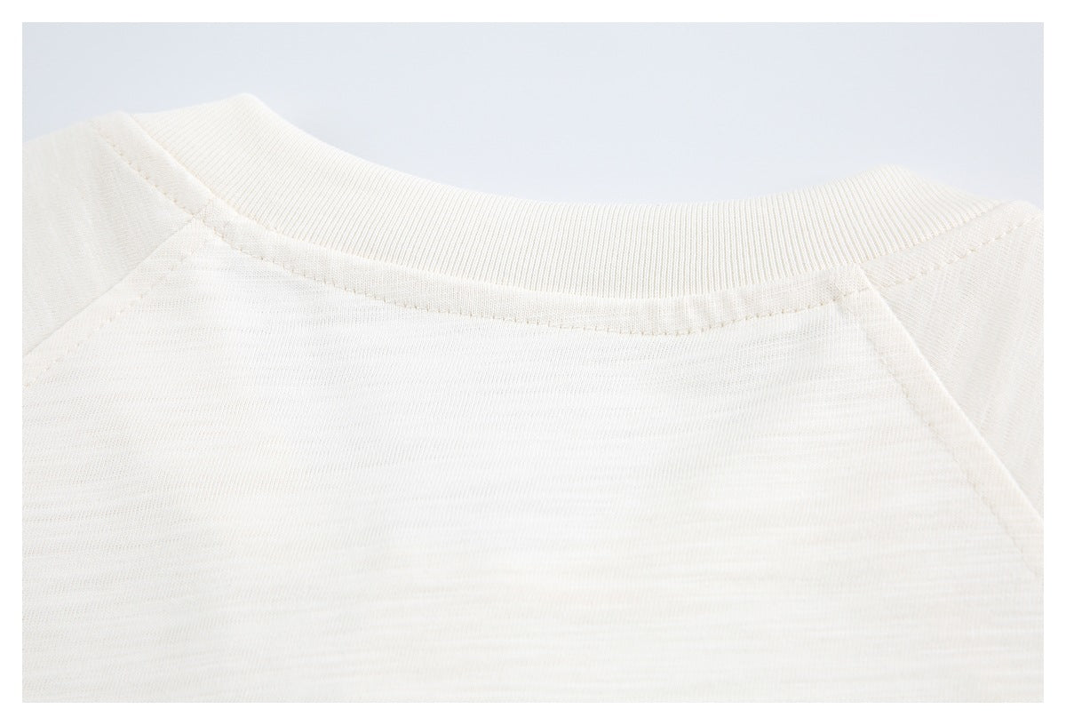 Close-up of an off-white ribbed crew neckline with raglan shoulder seams.